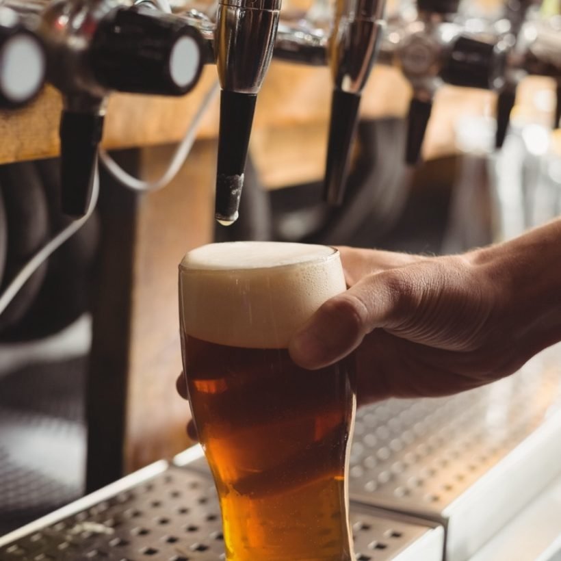 Close-up of bar tender filling beer from bar pump at bar counter